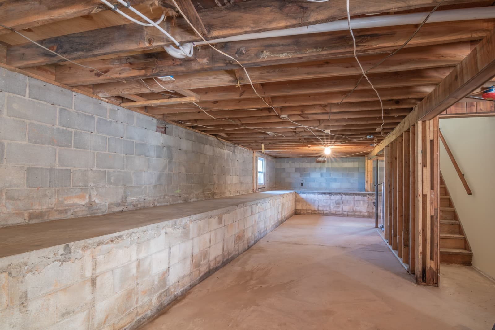 An empty basement room with a bare concrete floor