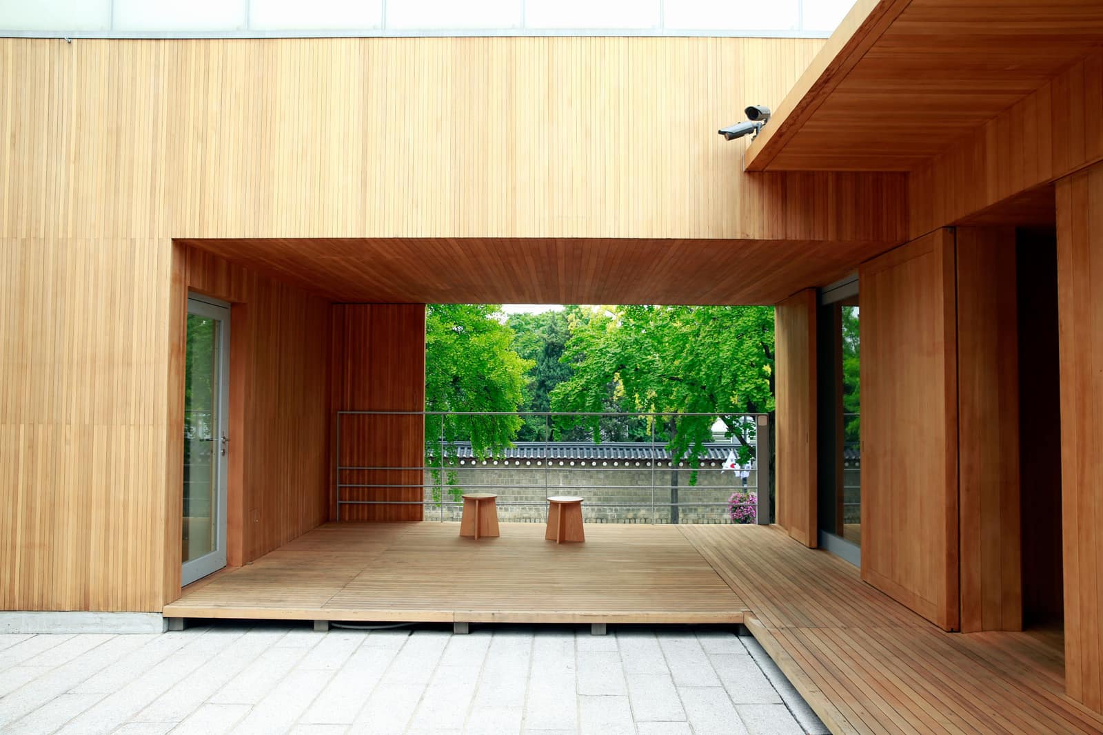 Two wooden stools side by side on a patio with greenery behind them