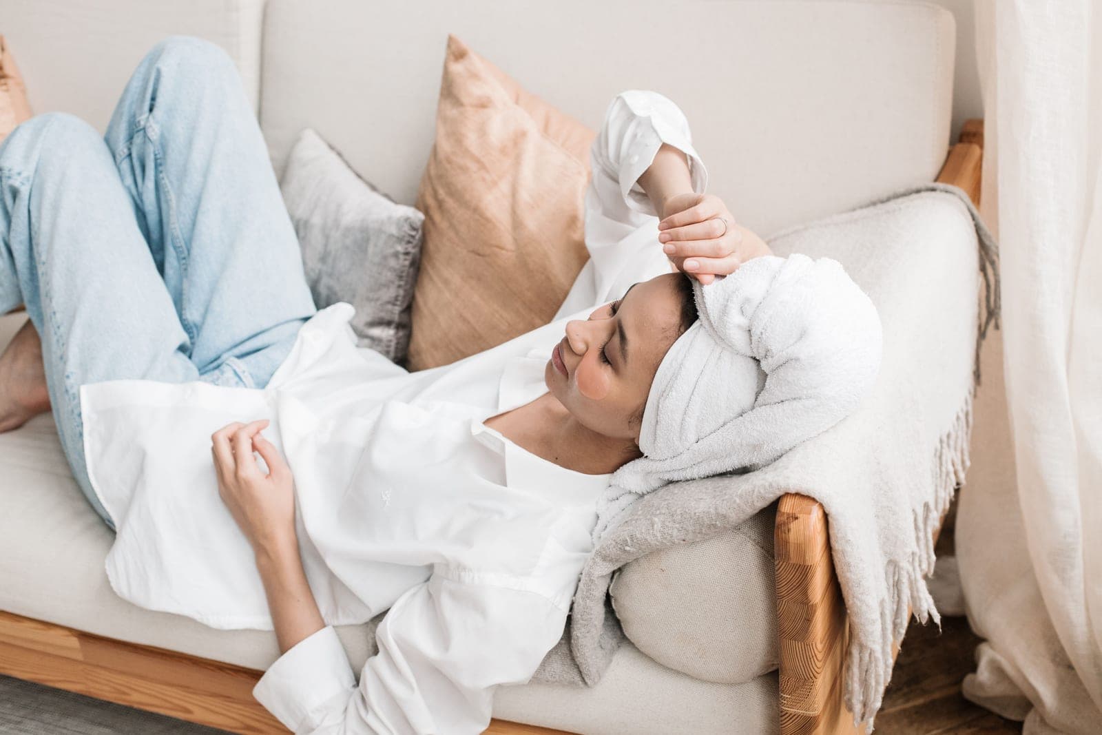 A person lying on a bed wrapped in a heated blanket with the controller beside them