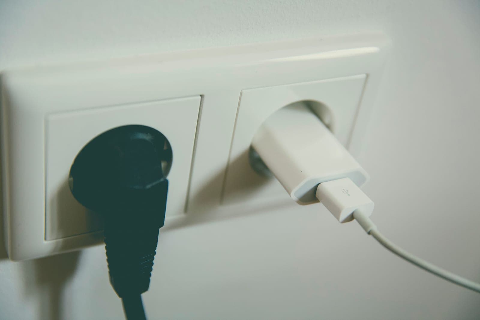 A power cord and wall socket beside a folded heated blanket