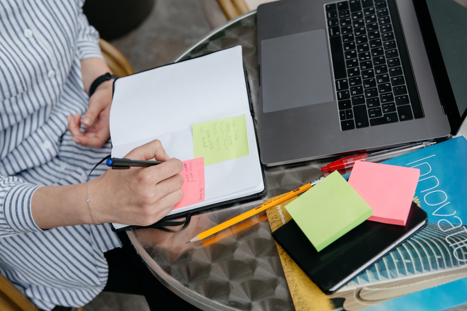 A person sitting with a notebook and pen, thinking